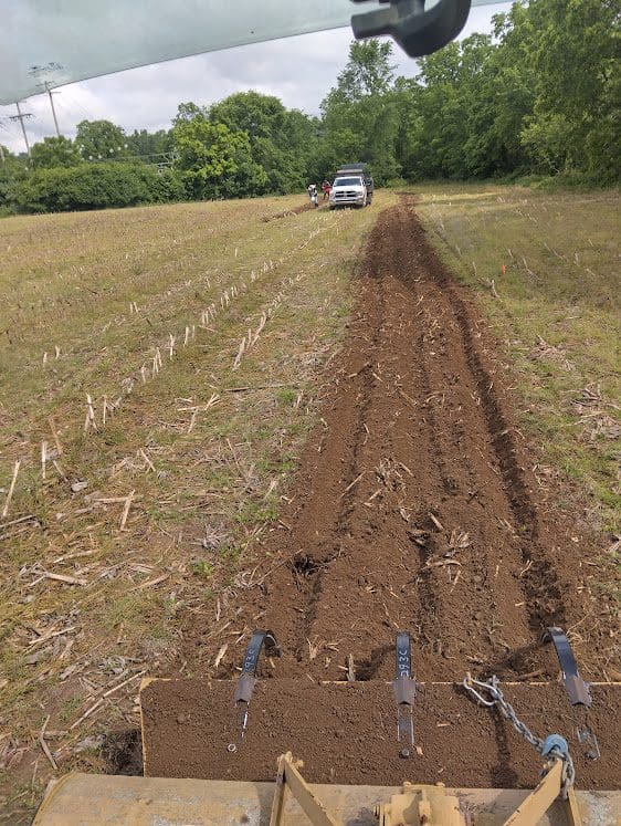 Tractor plowing furrow toward parked pickup